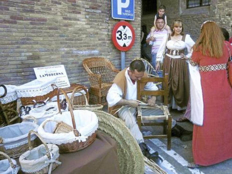 Un artesano elabora una cesta en uno de los puestos del mercado medieval.