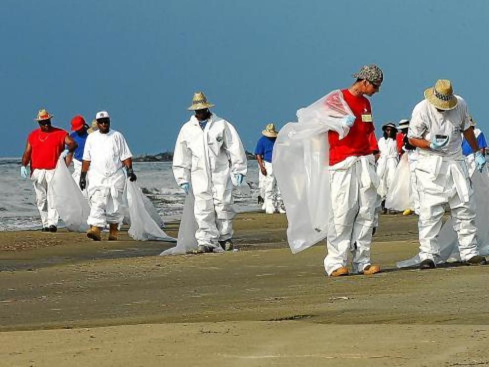 Un grupo de trabajadores contratados para limpiar las playas de Luisiana rastrean la arena en busca de restos de crudo.