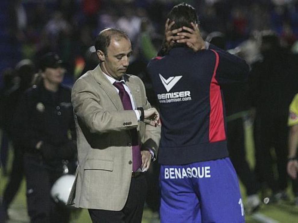 El técnico del Huesca Antonio Calderón mira su reloj con gesto serio.
