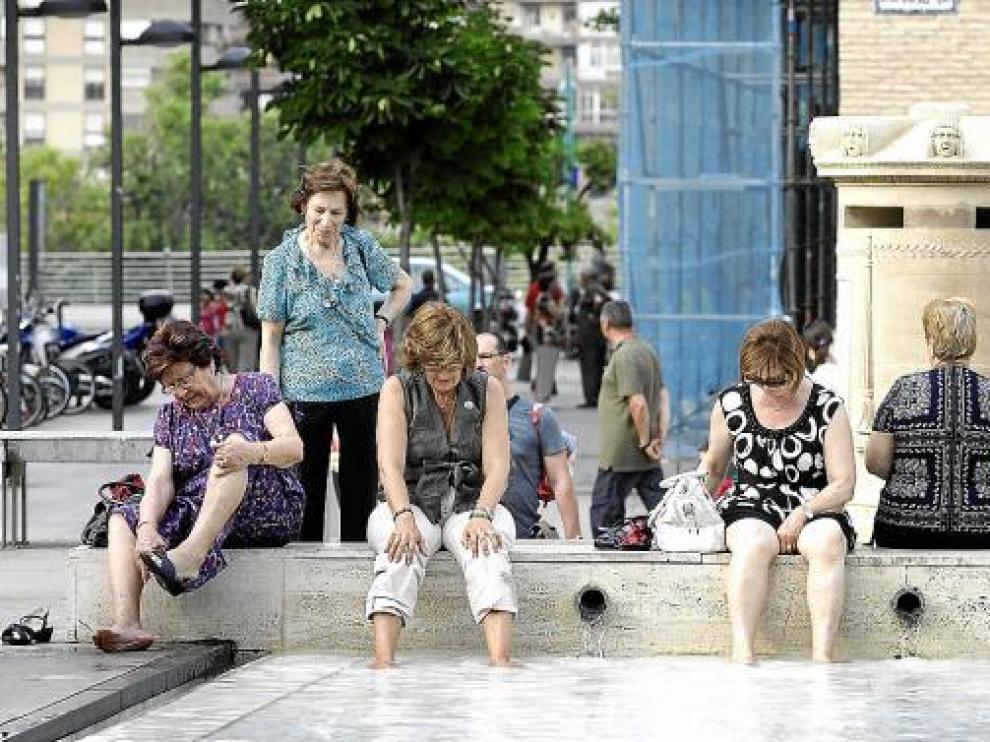 Unas mujeres se refrescaban ayer los pies en la plaza del Pilar de Zaragoza.