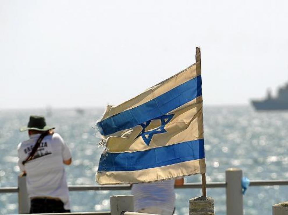 Unos israelíes observan, junto a la bandera de su país, el buque 'Rachel Corrie', que ayer fue abordado por el Ejército.