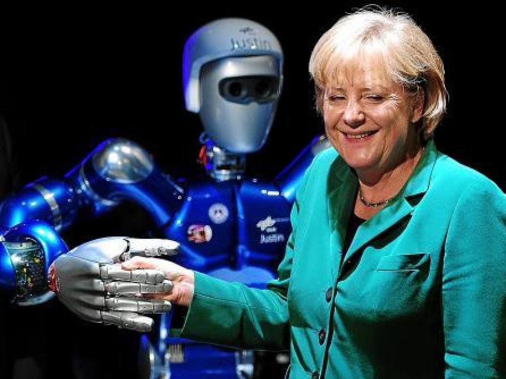Merkel sonríe al dar la mano al robot 'Justin' durante la Feria Aeronáutica de Berlín, ayer.