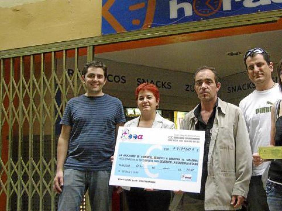 Luis Miguel García, el padre de Aitana (en el centro), recibe el cheque de los comerciantes.