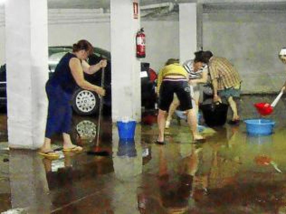 Los vecinos achican agua en el garaje de un edificio de Grañén.