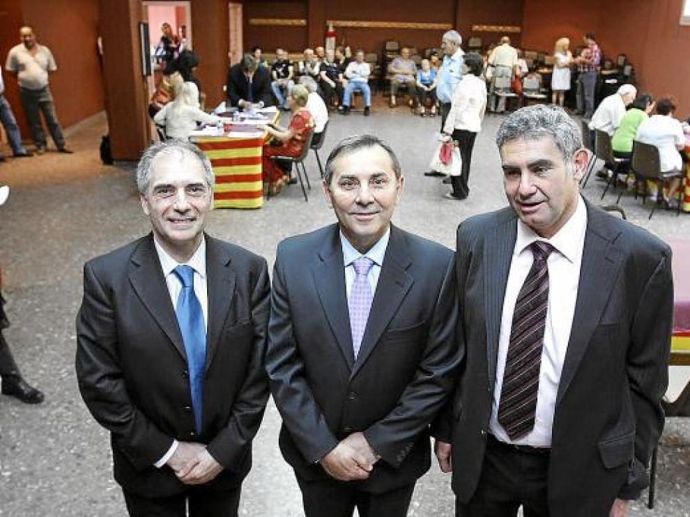 El alcalde, Ángel Torres, flanqueado por dos de los socios de ILD. Al fondo, entrega de los cheques.