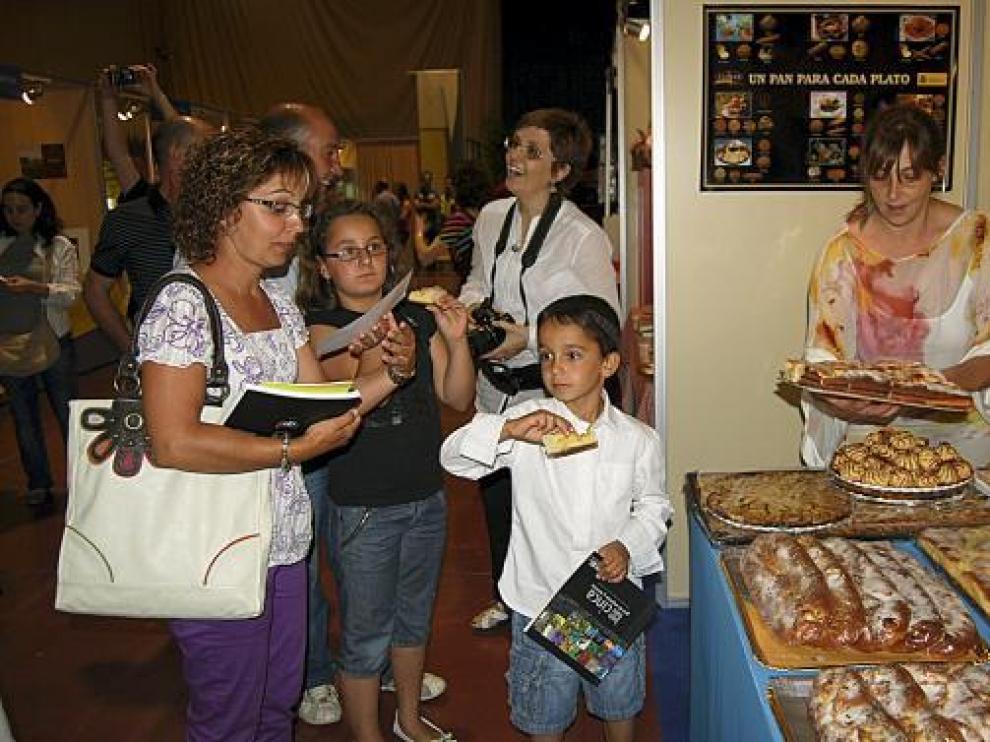 Varios visitantes degustan dulces de Velilla de Cinca en uno de los puestos de la feria.