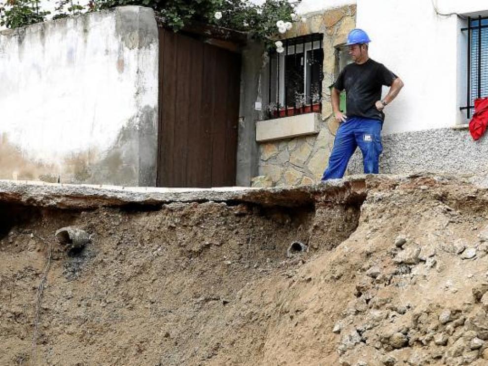 Un operario delante de una de las casas desalojadas por el derrumbe del talud.