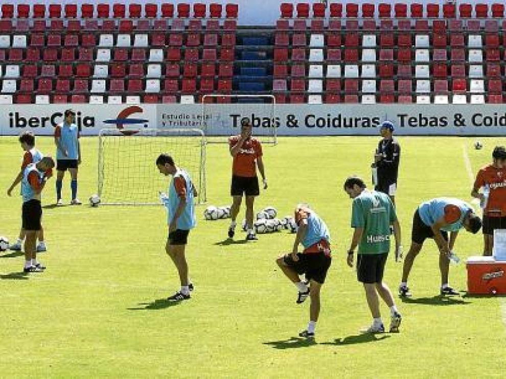 Los jugadores del Huesca, durante un interludio del entrenamiento de ayer durante el que se hidratan con agua.