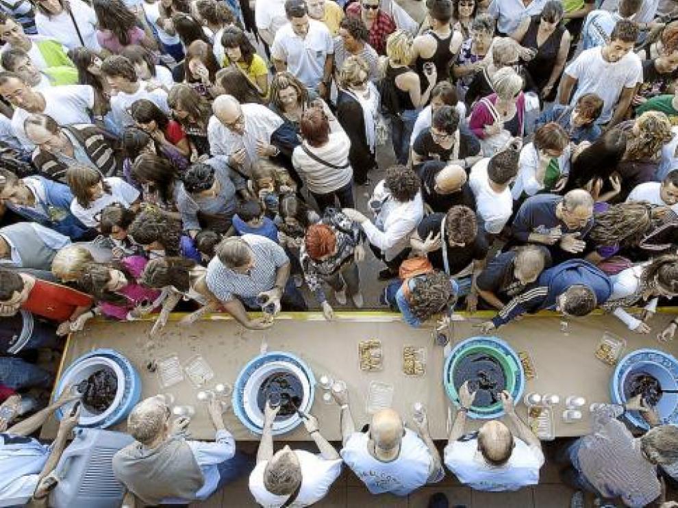Los miembros de la peña El Cohete de Utebo sirvan sangría a los vecinos tras el chupinazo.