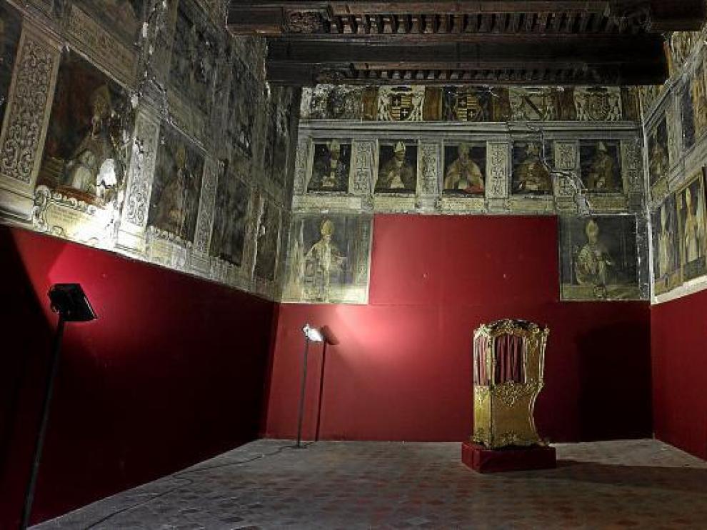 Interior del Salón de Obispos del palacio arzobispal, con el artesonado restaurado y las pinturas deterioradas.