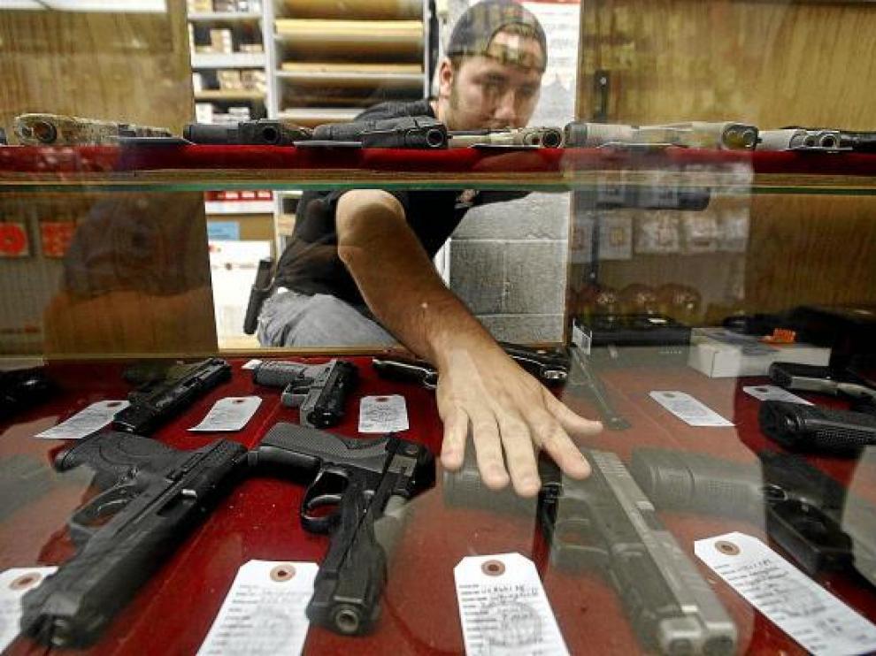 Un dependiente enseña las armas que vende en Wichita (Kansas), EE. UU.