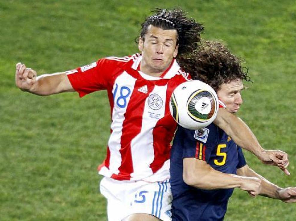 Puyol salta con el jugador paraguayo Nelson Valdez durante el partido de anoche.