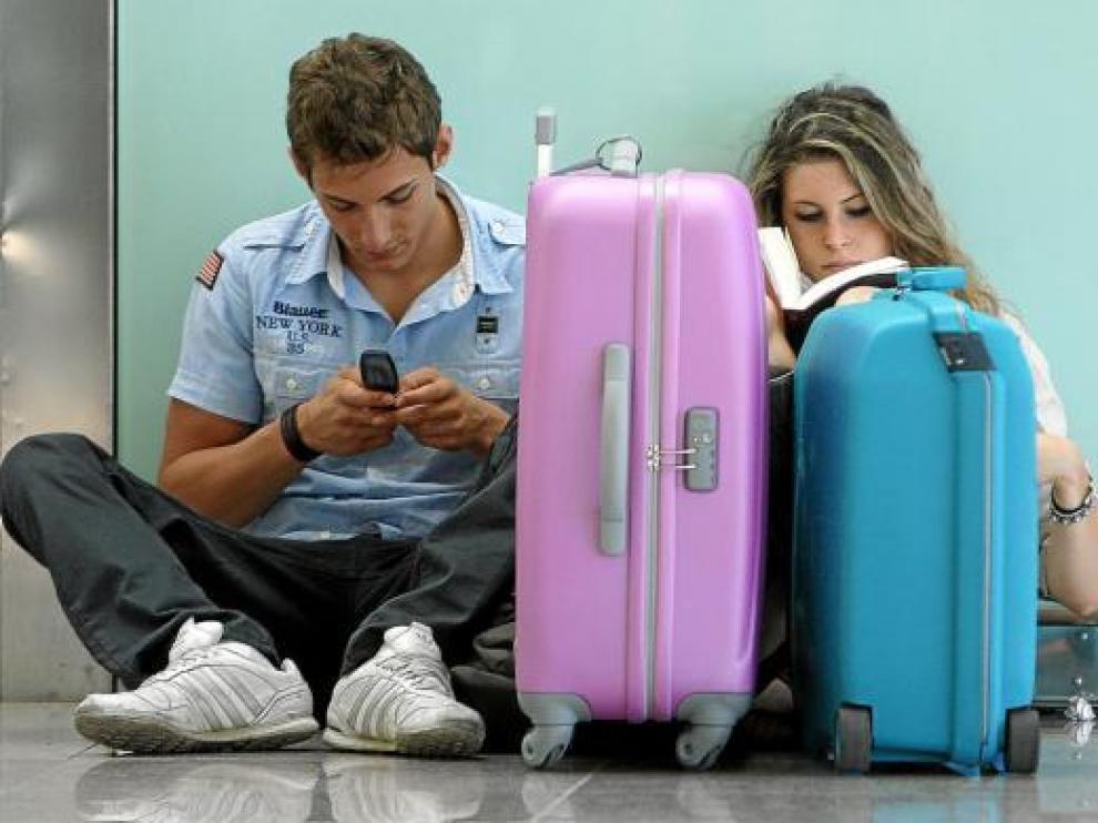 Dos jóvenes, de espera ayer en el aeropuerto del Prat, afectado por la huelga francesa de controladores.