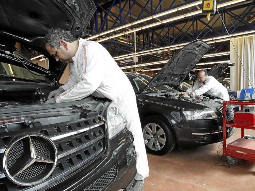 Dos trabajadores de Centro Zaragoza trabajan para identificar dos coches de alta gama recuperados estos días.