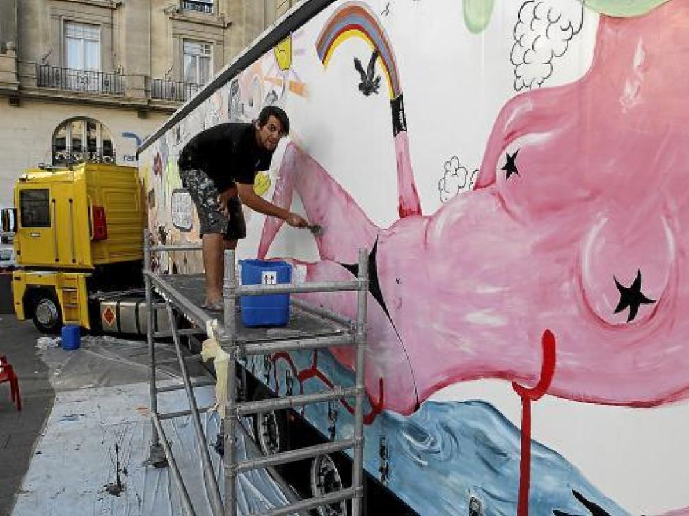 El artista Leto da las últimas pinceladas a su pintura mural en el lateral del remolque.