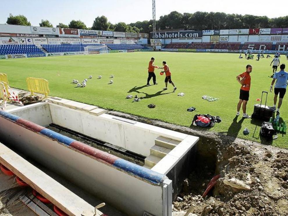 Los jugadores del Huesca, durante el entrenamiento de ayer en El Alcoraz. En primer término, las obras en los banquillos.
