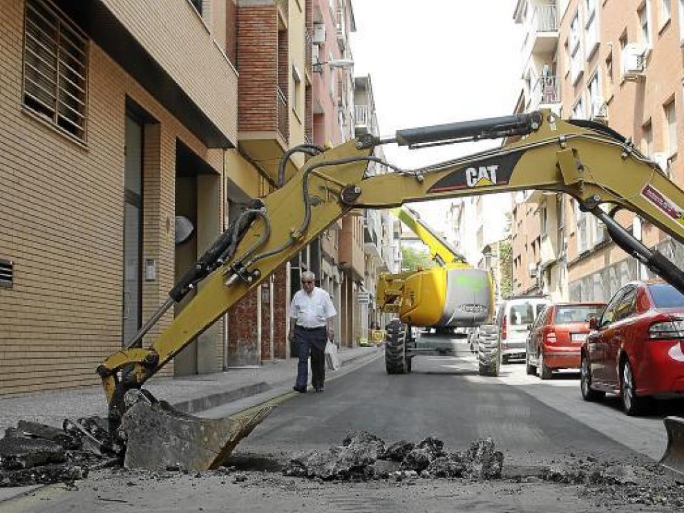 El asfalto recién estrenado vuelve a levantarse. Al fondo, otra grúa coloca las nuevas farolas.