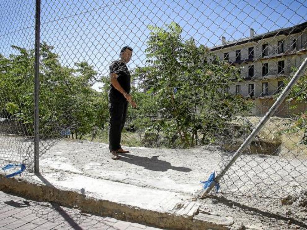 Javier muestra el agujero de la valla por la que entran personas a un solar para consumir drogas.