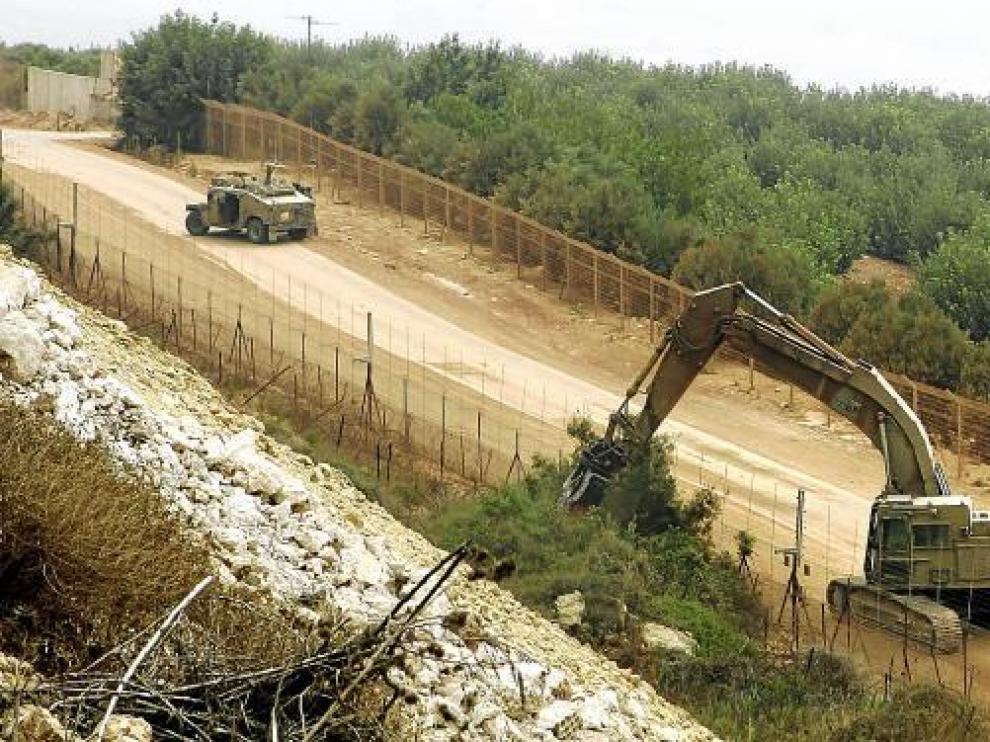 Una grúa del Ejército israelí tala árboles, ayer en la frontera próxima al poblado libanés de Adeise.