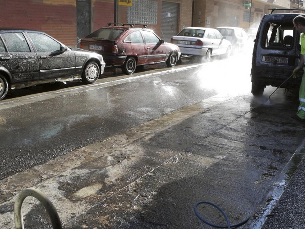 Operarios limpian una zona afectada por la quema de contenedores en una imagen de archivo