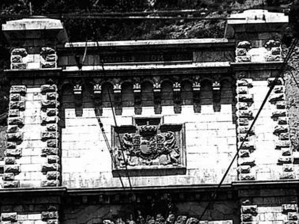 Escudo original de 1928 con corona monárquica. El túnel fue inaugurado el 18 de julio por Alfonso XIII y el presidente de la República Francesa, Gaston Doumerguen. Hasta la dictadura, en la boca española del paso subterráneo lucía esta obra de cantería.