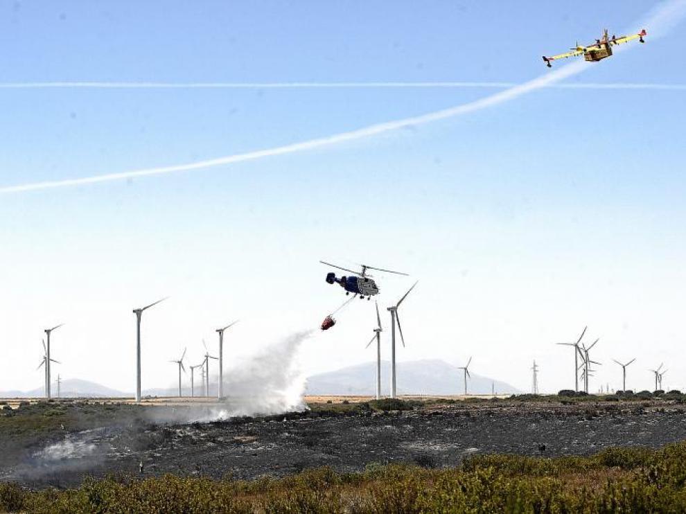 Un helicóptero echa agua sobre las llamas mientras un hidroavión sobrevuela la zona del incendio.