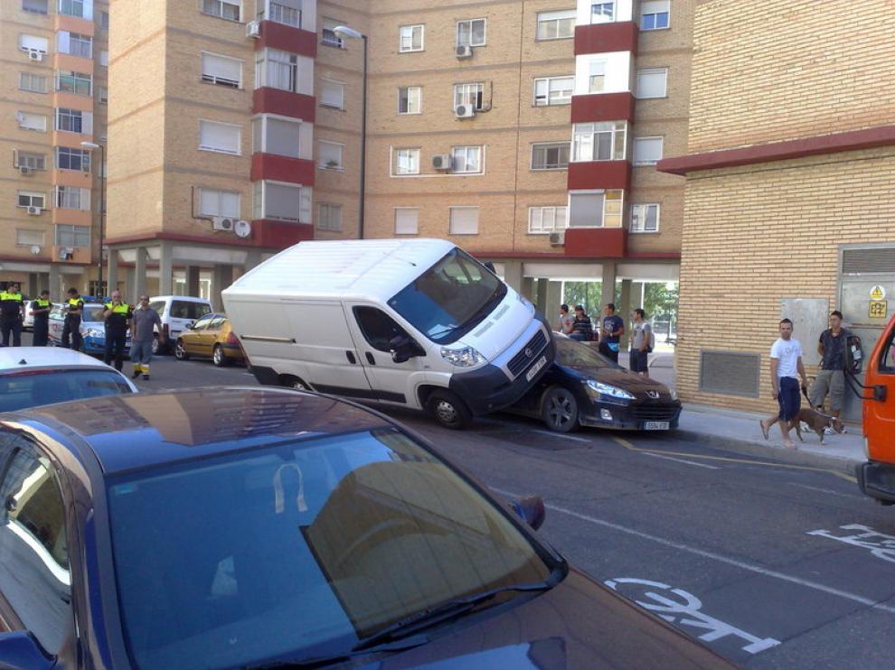 Una furgoneta se ha subido encima de un coche aparcado