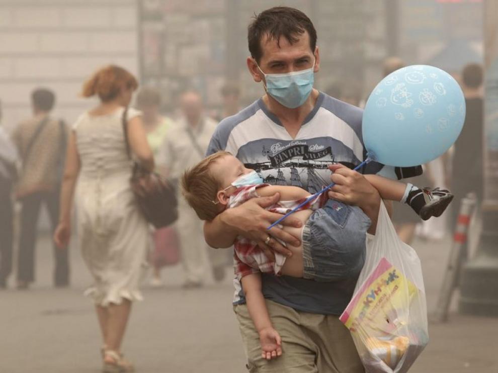Un par de viandantes se protegen de la contaminación ambiental con mascarillas en el centro de Moscú