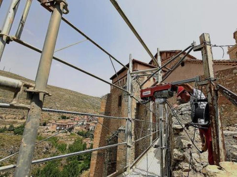 Un operario accede al andamio sobre el río. Al fondo, la catedral.
