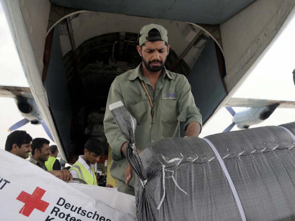 Un equipo de trabajadores descarga ayuda humanitaria donada por la Cruz Roja