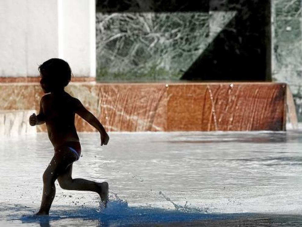 Un niño se refresca en la fuente de Goya en la plaza del Pilar de Zaragoza.