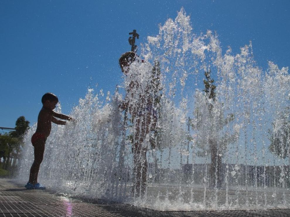 Un grupo de niños se refresca en una fuente