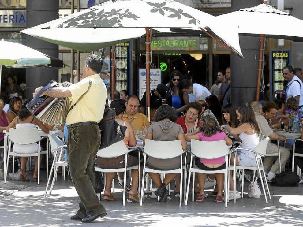 Un acordeonista toca en primer plano, mientras su compañero 'recauda' al fondo. Es la hora del vermú en las terrazas de la plaza del Pilar.