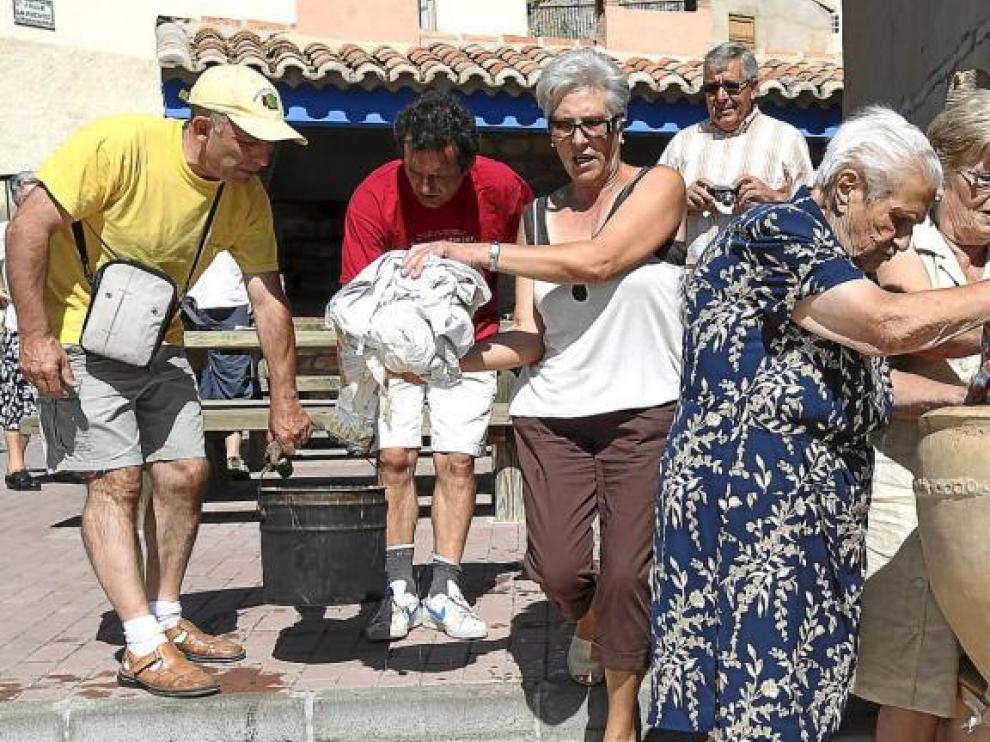 Asunción Cardo -de azul- y otras mujeres, llenan de ropa el 'cocio', en el que se echará ceniza y agua. Así se blanqueaban las prendas.