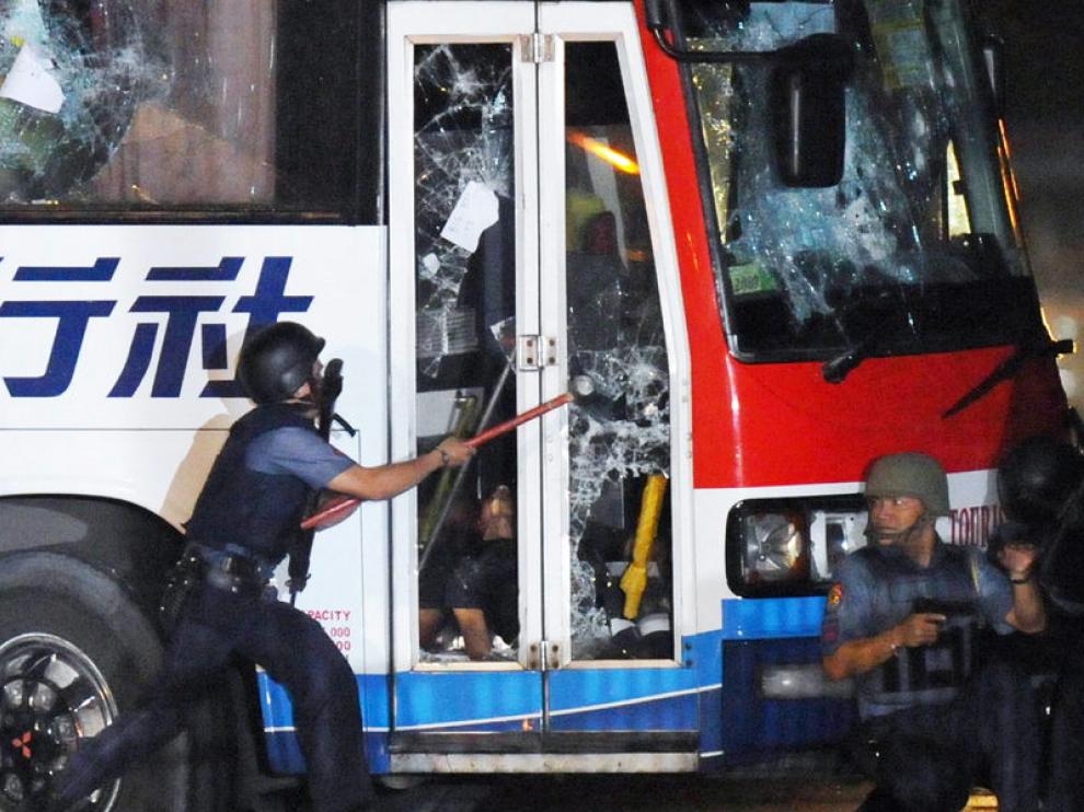 Un policía rompe el cristal de la puerta del autobús durante el tiroteo.