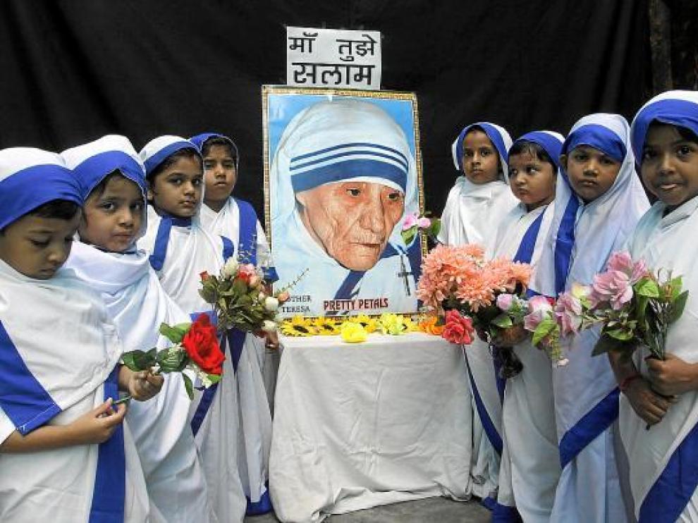 Niñas vestidas como Misioneras de la Caridad realizan una ofrenda floral en India, ayer.