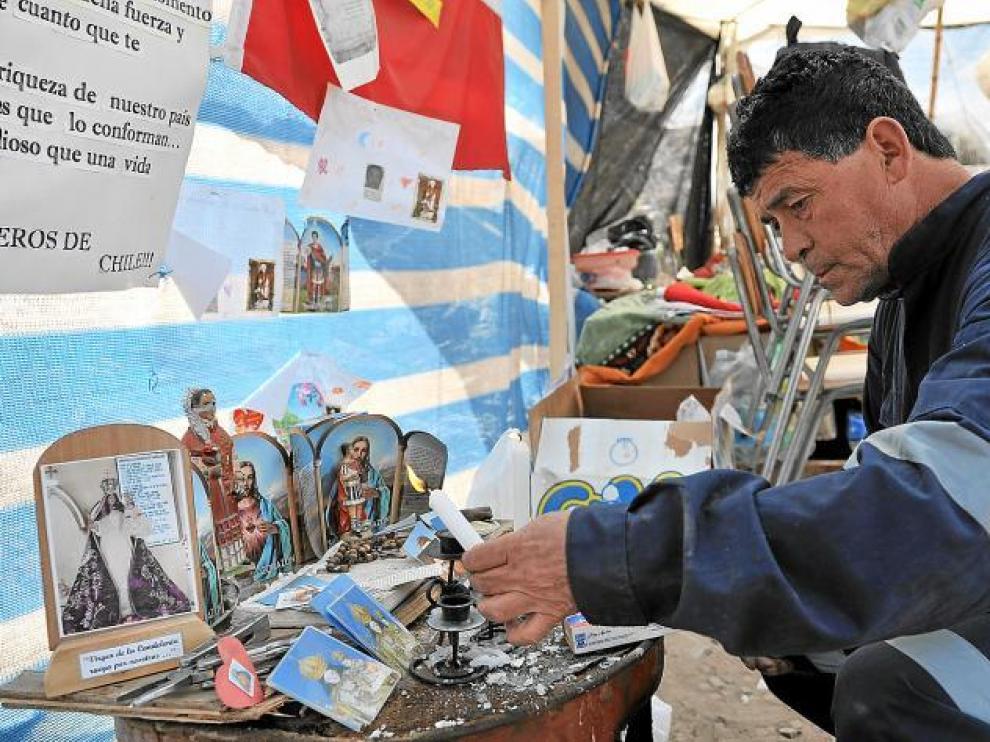 Un miembro de los equipos de rescate enciende una vela en el altar dedicado a los trabajadores de la mina de San José, ayer.