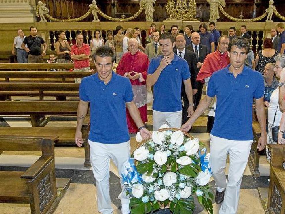 Los capitanes del Real Zaragoza, Gabi, Jorge López y Poncio, seguidos por la directiva y el capellán, llevan las flores al altar.