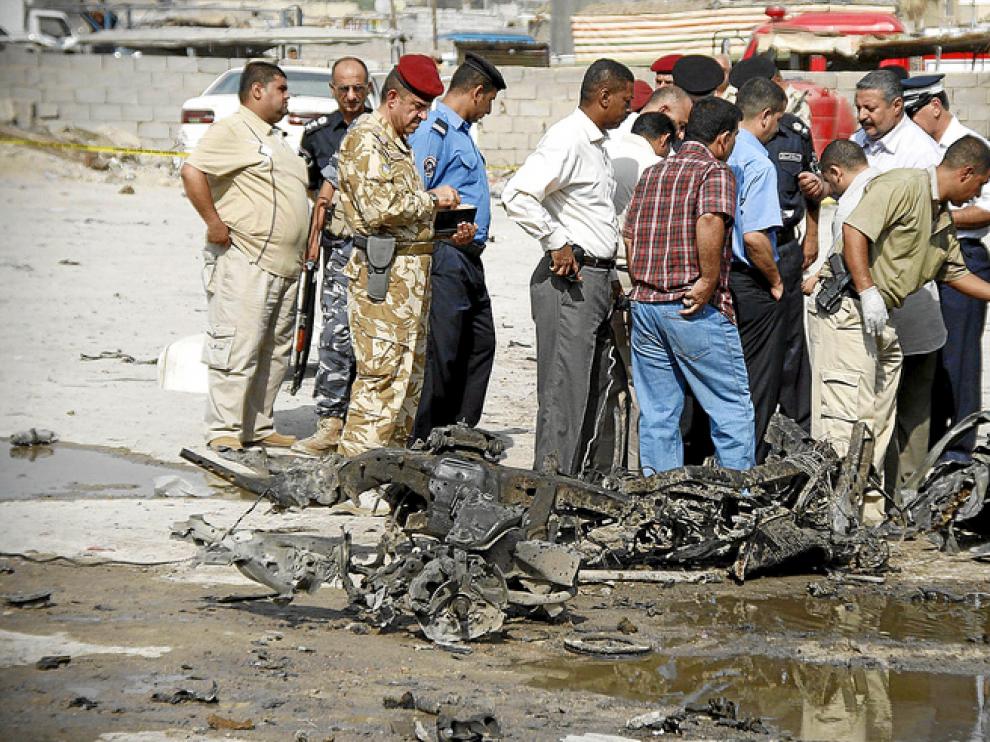 Miembros de la policía irquí inspeccionan el lugar donde explotó ayer un coche bomba en Basra, al sur de Iraq.