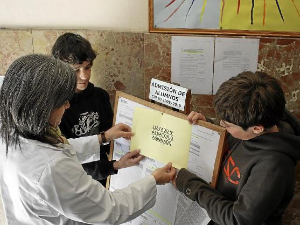 Una profesora y dos estudiantes colocan una lista de alumnos en el colegio Compañía de María.