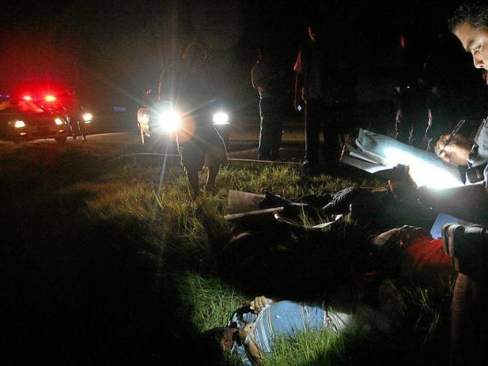 Un policía federal toma notas en una calle junto a uno de los 14 cadáveres encontrados en Acapulco, el pasado viernes.