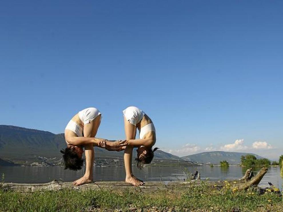 Dos mujeres practican un ejercicio de yoga junto al embalse de Yesa.