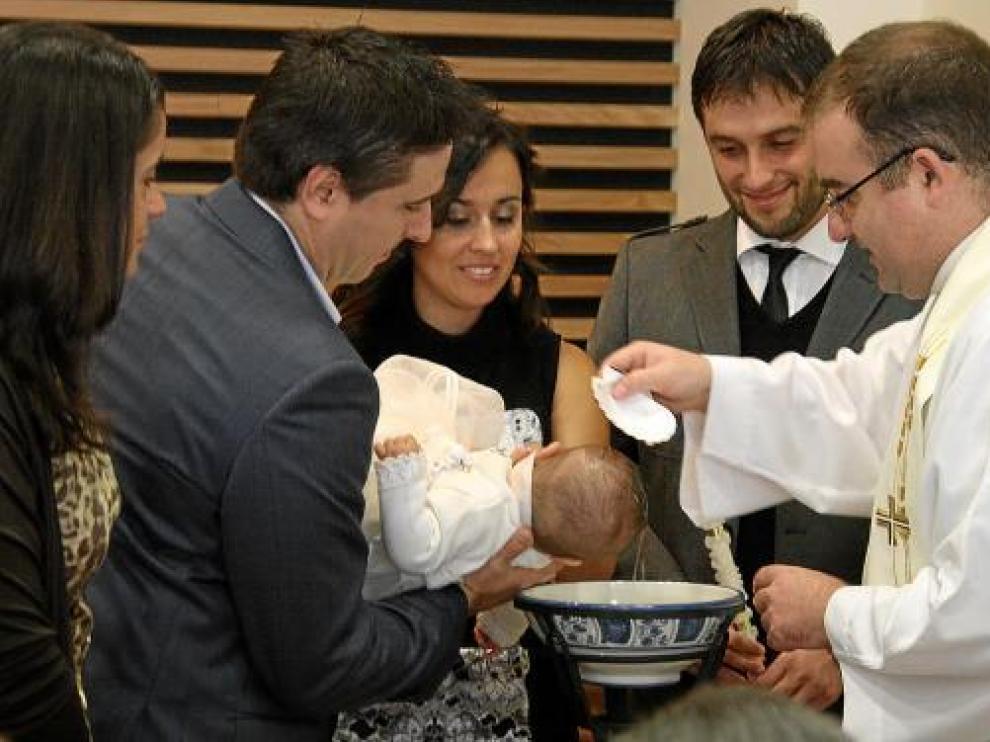 Jorge Ezquerro, con sus padres, padrinos -Cristina y Óscar- y el párroco Santiago Aparicio.