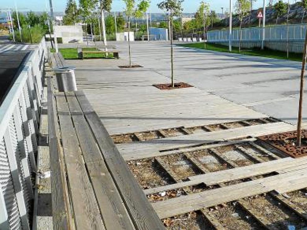 El pavimento de madera en las zonas de descanso con bancos está levantado. El aceite o barniz que deberían recibir estas maderas para su mantenimiento brilla por su ausencia.