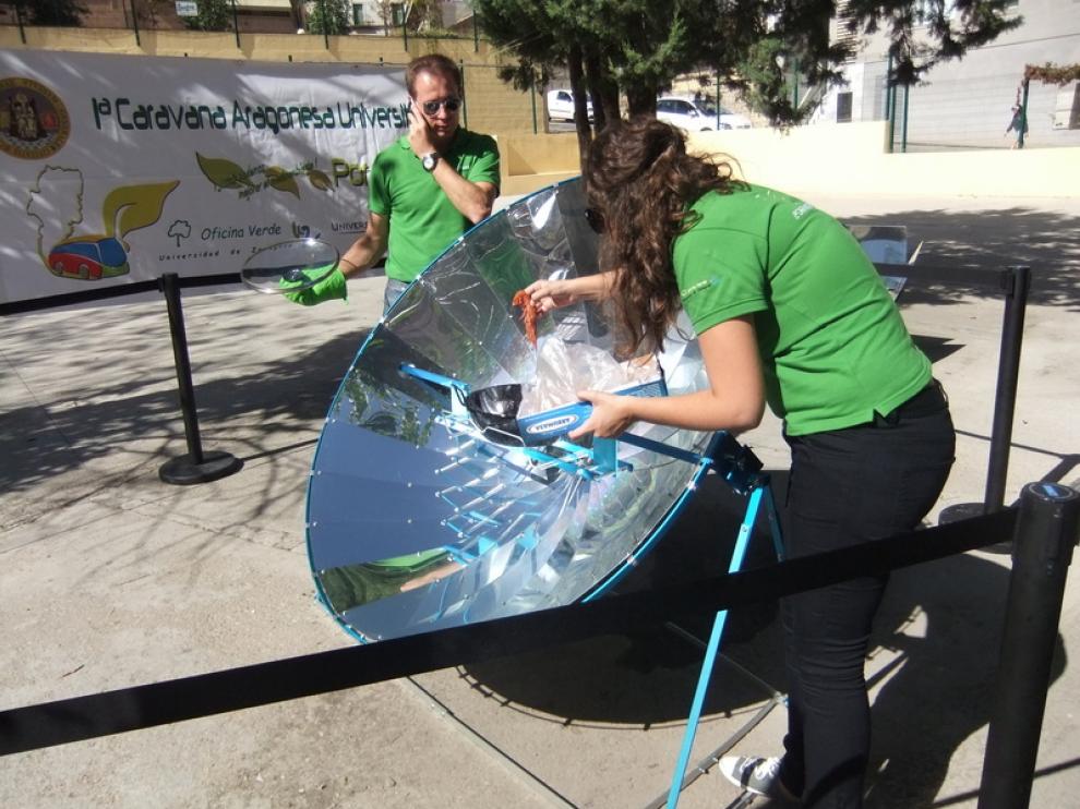 Una voluntaria acerca un langostino a la olla que recibe los rayos solares de la parabólica.