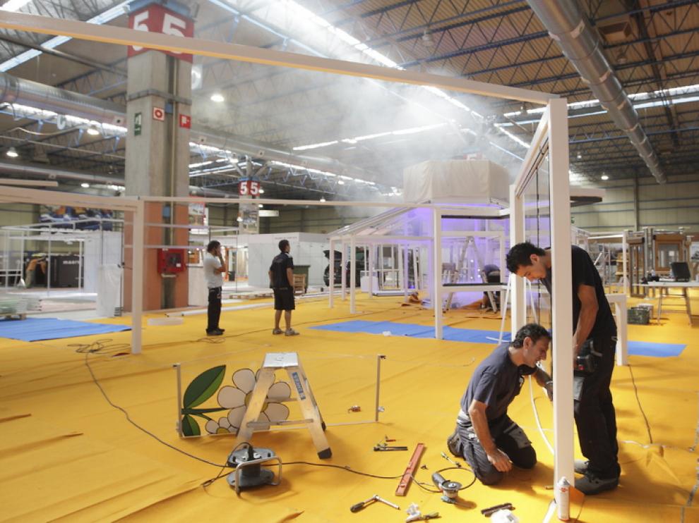 Unos obreros ultiman los preparativos en el interior de la Feria de Muestras