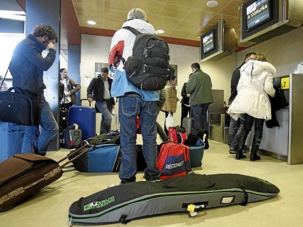 Viajeros del último vuelo de la pasada temporada con el material de esquí.