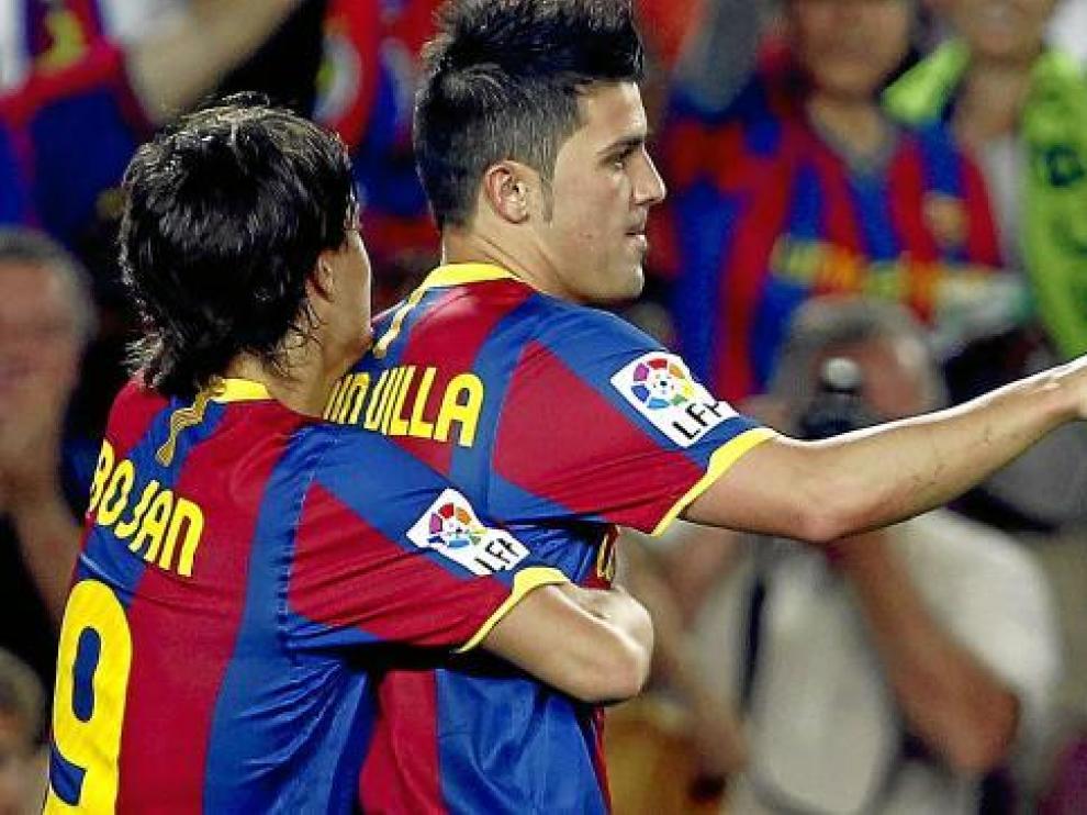 Bojan abraza a David Villa tras marcar un gol al Sporting.
