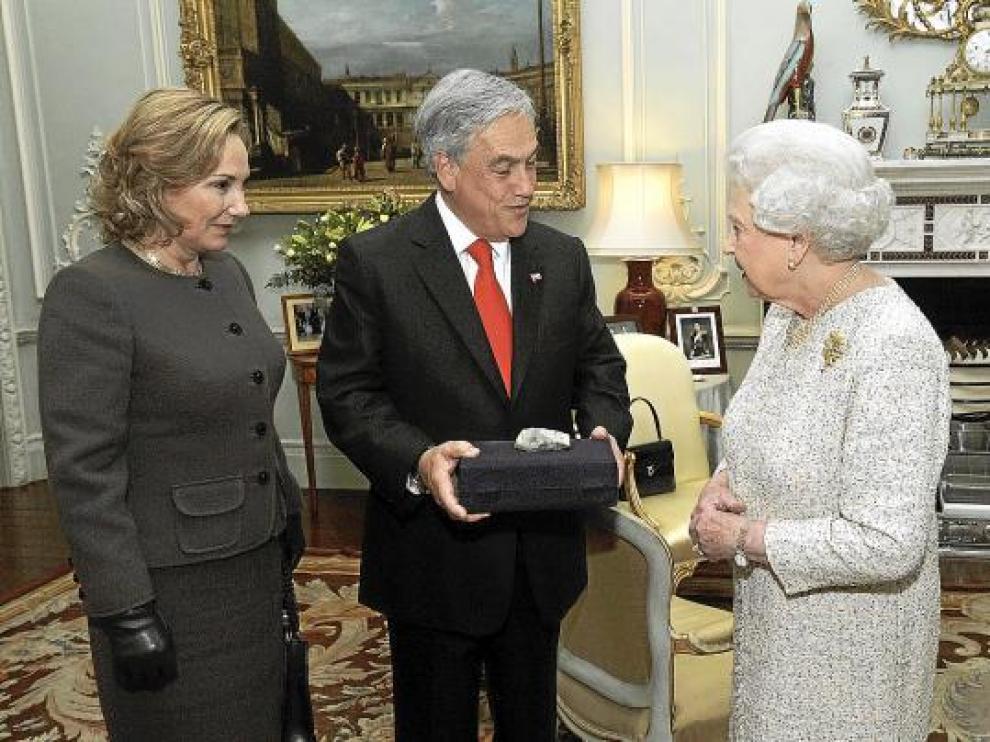 Isabel II recibe una piedra del pozo San José de manos de Piñera y su mujer, ayer en Londres.