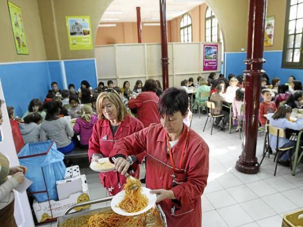 Una monitora sirve un plato de pasta en el comedor del colegio Gascón y Marín de Zaragoza.